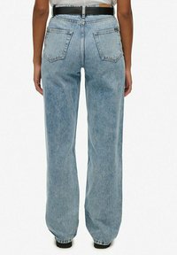 Lichtblauwe high-waisted jeans met een losse pasvorm, vijf zakken en een zwarte riem. Heeft een vervaagde wassing en een lichte textuur.