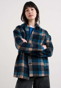 Volnen plašč v temno modri, teal in bež barvi z ovratnikom, gumbnim zapiranjem in širokimi rokavi. Ima teksturiran vzorec.