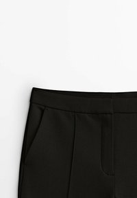 Pantalon noir sur mesure présentant une texture lisse, une ceinture structurée, des poches avant et un design épuré et minimaliste.