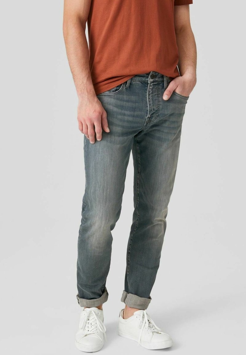 Ljusblå tampade jeans med en urblekt finish, med midjehöjd, fem fickor och uppvikta fållar, parat med vita sneakers.