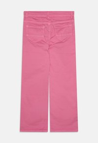 Jean large rose en coton. Dispose de deux poches arrière et d'une taille plate. Texture lisse, couleur uniforme sans motifs ni accents.