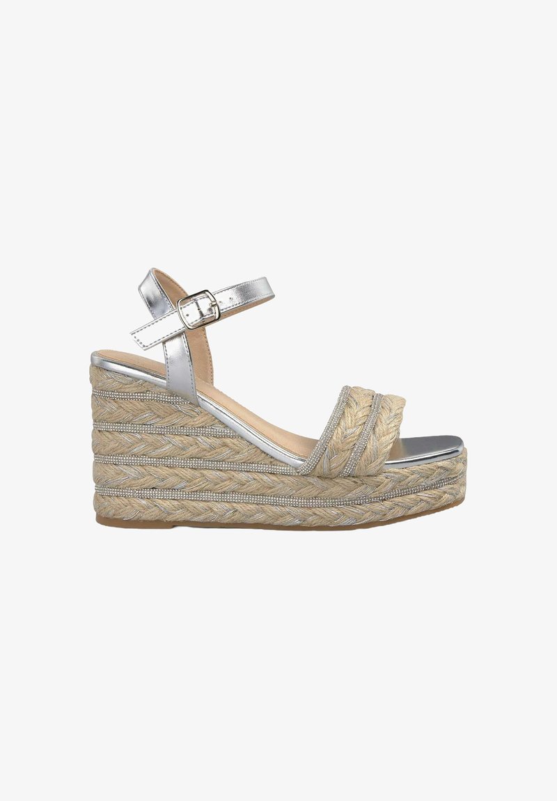 Silberne metallische Keilsandalette mit gewebter Jutemuster, ausgestattet mit zwei gekreuzten Riemen und einem geschnallten Knöchelriemen. Strapazierfähige Gummisohle.