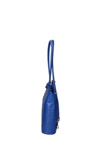 Sac en cuir bleu avec une surface texturée et bosselée, de longues poignées et des accents en métal argenté. Il présente une forme cylindrique étroite.