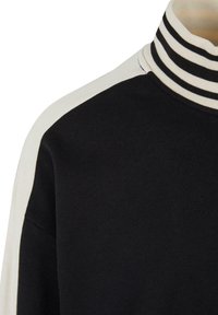 Sort sweatshirt med en hvid detalje på skulderen og en stribet krave i sort og hvid. Blød tekstur, afslappet design.