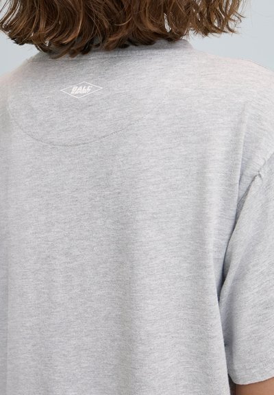 Pelēks kokvilnas T-krekls ar apaļu kakla izgriezumu un īsām piedurknēm. Aizmugurē netālu no kakla ir redzams neliels balts dimanta logotips.