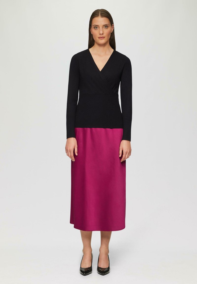 Langarmige jurk gemaakt van een zacht zwart breigoed top en een zijden magenta rok. Beschikt over een V-halslijn en een rechte silhouet, gecombineerd met zwarte hakken.