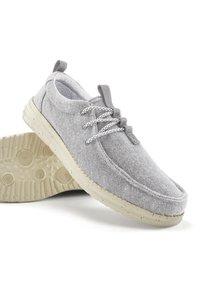 Helle graue Stoffschuhe mit strukturiertem Obermaterial, ausgestattet mit grauen Schnürsenkeln und einer beige gesprenkelten Gummisohle. Abgerundete Zehenkappe und niedriges Profil.