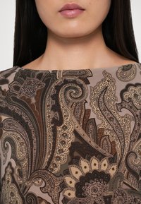 Καφέ ύφασμα με πασχαλισμένο μοτίβο και περίπλοκα σχέδια σε μπεζ, σκούρο πράσινο και οξύ χρώμα. Λείο υλικό; ορατό στρογγυλό λαιμό.