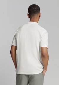 Korte mouwen polo shirt in witte stof met een zachte, gladde textuur en een klassieke kraag; heeft een relaxte pasvorm en subtiele stikseldetails.