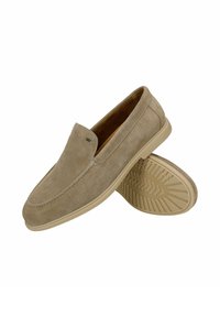 Mocassins beige en daim à enfiler avec des détails cousus et des semelles en caoutchouc texturées, une chaussure reposant sur le côté montrant le motif de la semelle.