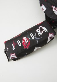 Schwarzes Stoffmäppchen mit roten und weißen Basketball-Trikotmustern, Reißverschluss und auffälligem "JORDAN"-Schriftzug.
