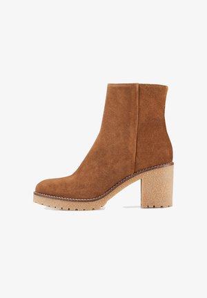 Bottine en daim marron avec un talon épais texturé, des panneaux élastiques latéraux et un bout arrondi, dotée d'une semelle contrastante de couleur claire.