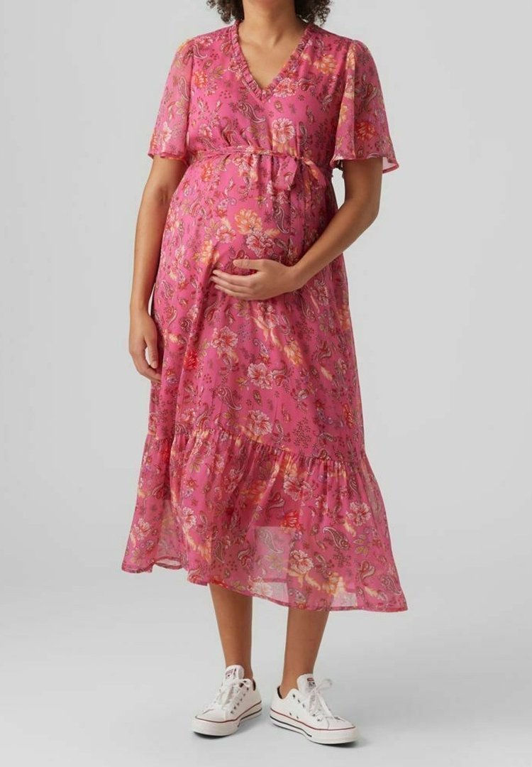 Robe midi à fleurs roses avec manches courtes, décolleté en V et taille froncée. Fabriquée en tissu léger avec un ourlet à volants. Accompagnée de baskets blanches.