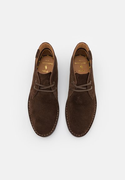 Zapatos de ante marrón con cordones, de diseño de punta redondeada, con detalles cosidos a lo largo de la suela y un forro interior suave.