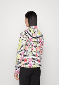 Blumenjacke mit schwarz-weißem Streifenmuster, verziert mit leuchtend pinken, grünen und orangefarbenen Blumen. Maßgeschneiderter Schnitt mit langen Ärmeln.