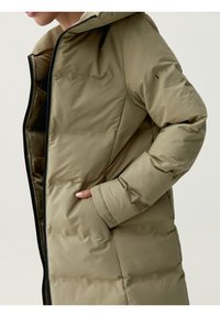 Khaki puffjacka med huva, med dragkedja fram, sidofickor och sömdetaljer. Materialet verkar slätt och isolerat.