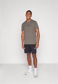 Gray athletic t-shirt with black logo, paired with black shorts and white athletic shoes. Simple design, lightweight fabric, and relaxed fit.