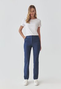 Blauwe spijkerbroek met een rechte pasvorm, met een middelhoge taille en een zachte textuur, gecombineerd met een wit T-shirt met korte mouwen.