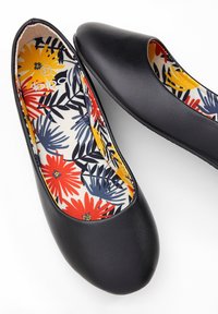 Ballerine sintetiche nere con punta arrotondata. L'interno presenta un motivo floreale in rosso, giallo e blu su uno sfondo chiaro.
