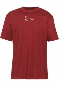 Rød bomulds t-shirt med rund hals og korte ærmer, med hvid broderet tekst på brystet. Blød tekstur og afslappet pasform.