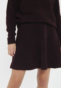 Burgunderfarbener, strukturiert gestrickter Pullover und passender Rock, beide mit einer weichen, flauschigen Oberfläche, im lässigen Schnitt und mit einem leicht ausgestellten Saum.