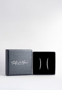 Silverfärgade hoopörhängen med en vriden design, presenterade i ett svart sammetfodrat displayfack med en texturerad yta och logotyp.