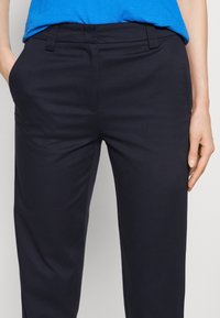 Navyblauwe op maat gemaakte broek met een soepel textuur, voorzien van zijzakken en een riemlus tailleband. Schone lijnen versterken het gestructureerde ontwerp.