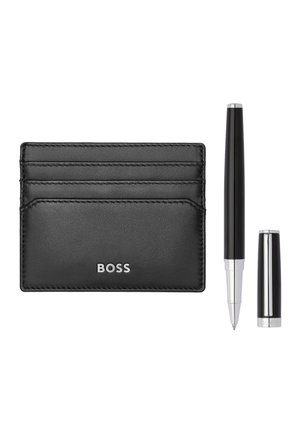 Portacarte BOSS in pelle nera con quattro scomparti per carte accanto a una penna a sfera nera e argento senza cappuccio.
