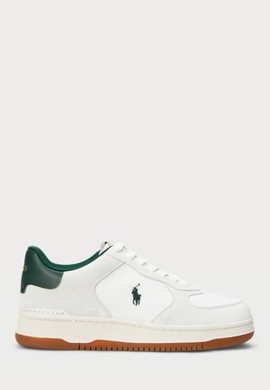 Hvit sneaker med grønne detaljer. Laget av semsket skinn og lær, med rund tå, flate snører og gummisåle med teksturert grep.