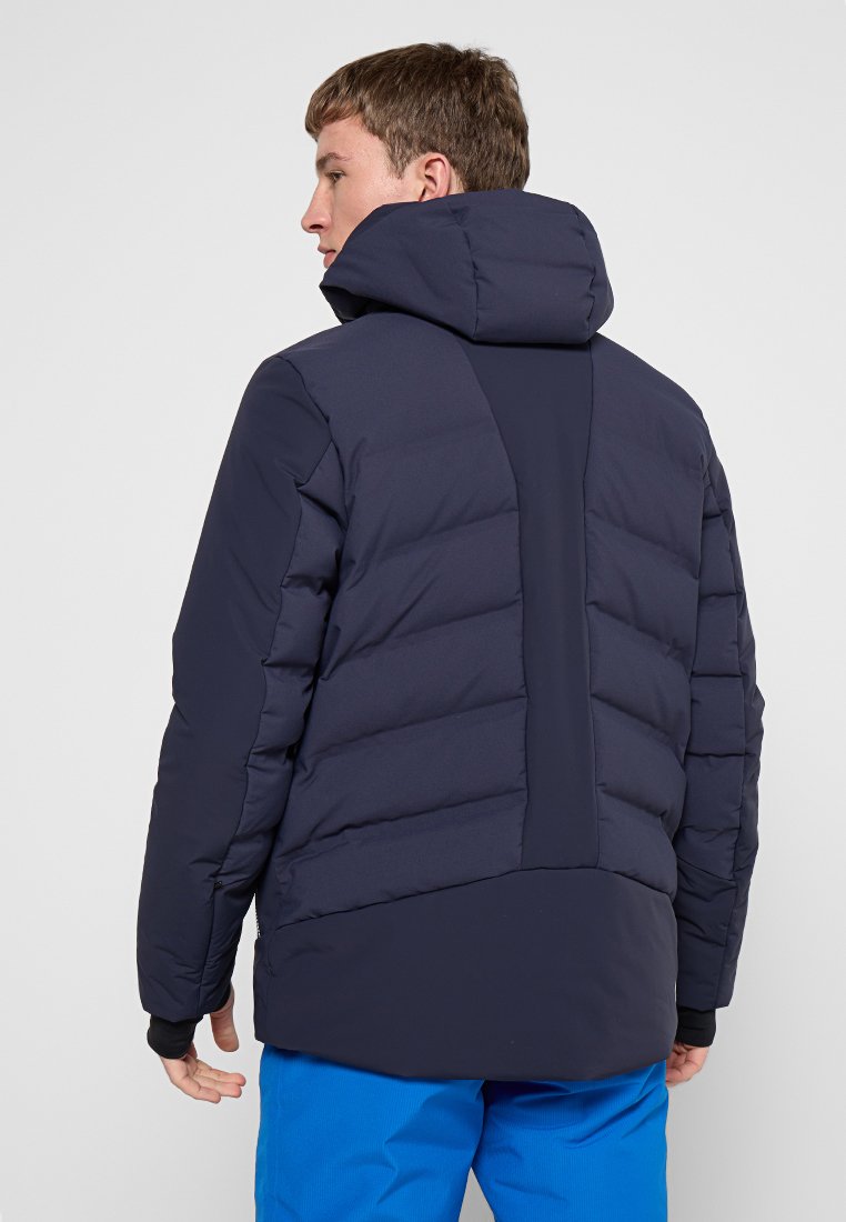 Giacca puffer blu navy con colletto alto, caratterizzata da un design a cuciture orizzontali e un pannello posteriore a contrasto. Tessuto morbido e isolato.