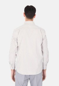 Camicia a righe con maniche lunghe, caratterizzata da strisce verticali bianche e marroni chiari, colletto a puntina e polsini con bottone.