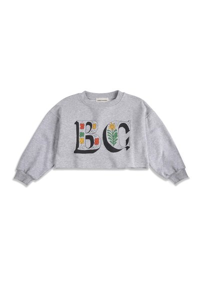 Sweat-shirt gris raccourci à manches longues, avec de grandes lettres décoratives "B" et "C" ornées de fleurs colorées sur le devant.