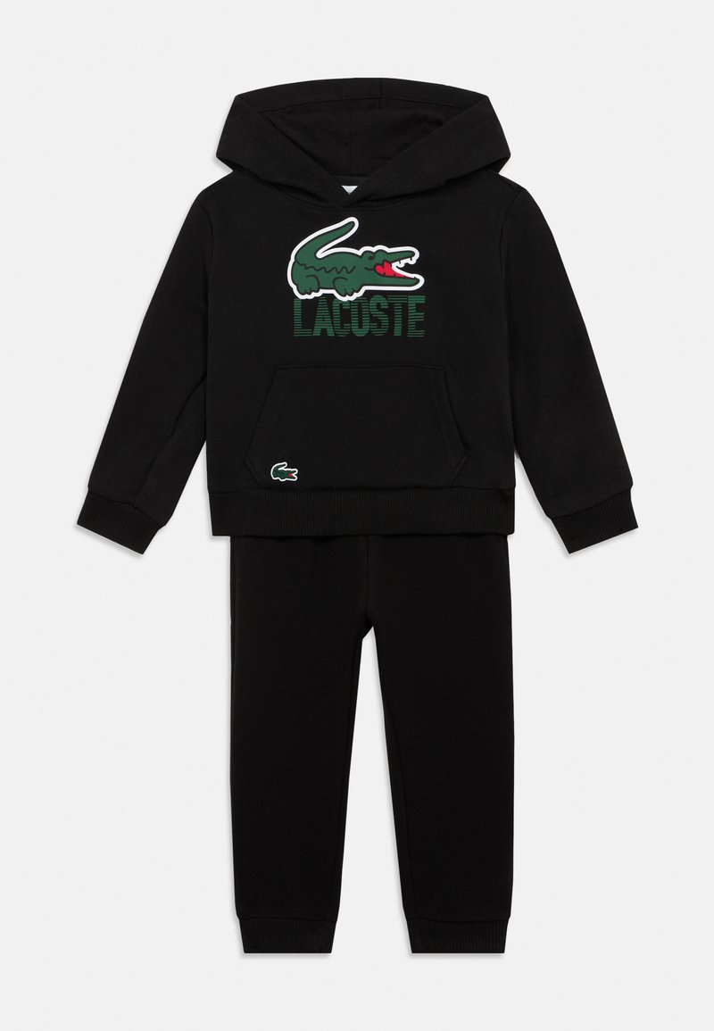 Conjunto de sweatshirt com capuz e calças para crianças negras, com o logo do crocodilo verde da Lacoste e o nome da marca no peito.