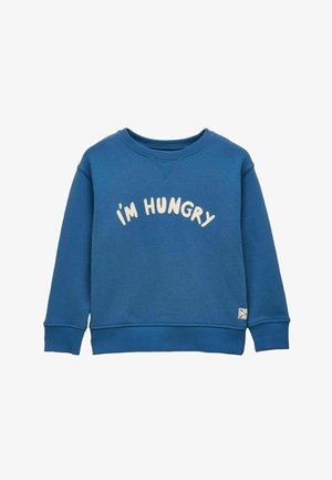 Mėlynas ilgomis rankovėmis džemperis su banguotais rankogaliais ir apačia, ant krūtinės ryškiais šviesios spalvos dideliais raidėmis užrašyta frazė "AŠ ALKANAS".