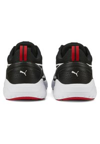 Zapatillas deportivas negras con una parte superior de malla texturizada, entresuela blanca y detalles rojos en la pestaña del talón y la suela.