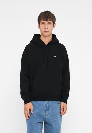 Black hooded sweatshirt with a front pocket and small white "OBEY" logo on the chest. Worn with light blue denim pants.