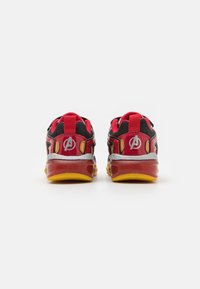 Rote, schwarze und metallische Sneaker mit einer gelben Sohle. Sie verfügen über Logo-Akzente und strukturierte Details im Obermaterial. Niedriges, schnürsenkelloses Design.