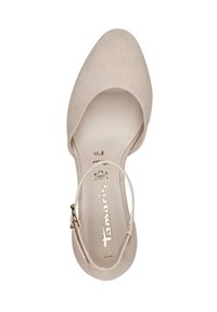 Scarpa con tacco alto in suede beige, con punta affusolata, cinturino alla caviglia e un logo metallico sulla soletta. Texture liscia, design elegante.