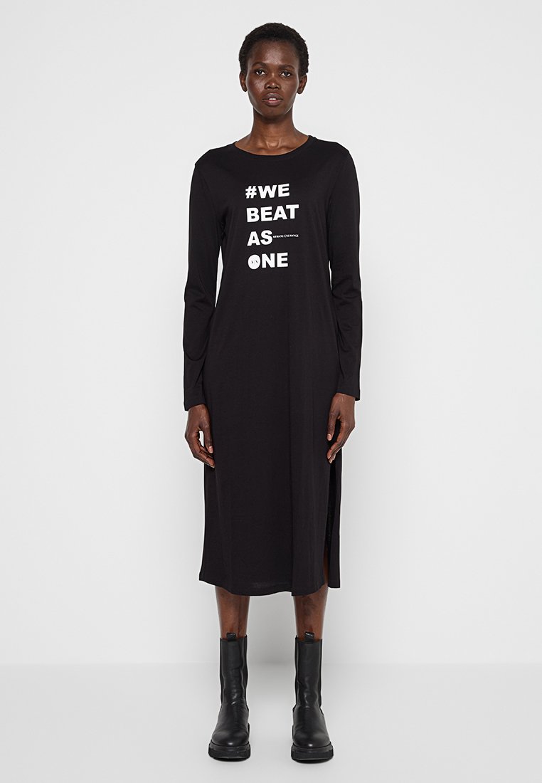 Abito nero a maniche lunghe con la scritta "#WE BEAT AS ONE" in bianco, dotato di spacco laterale, realizzato in un tessuto morbido e liscio.