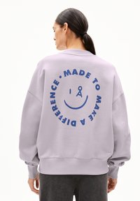 Lila sweatshirt met een boxy ontwerp, voorzien van een grote blauwe grafische print op de achterkant met de tekst "MADE TO MAKE A DIFFERENCE" en een glimlachend gezicht.