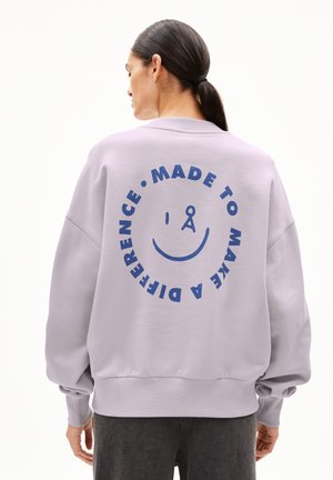 Lila Sweatshirt mit boxy Design, versehen mit einem großen blauen Grafik auf der Rückseite, die "MADE TO MAKE A DIFFERENCE" mit einem Smiley zeigt.