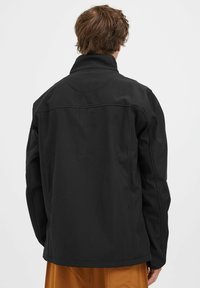 Fekete softshell dzseki magas gallérral, letisztult vonalakkal és rugalmas mandzsettákkal. Simául tapintható textúrával és egyszerű, minimalista dizájnnal rendelkezik.