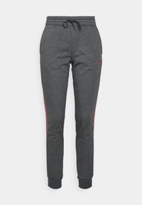 Pantalones deportivos gris oscuro con cintura elástica y cordón negro, ajuste estrecho con franjas granate a los lados y logo de Adidas granate en el muslo izquierdo.
