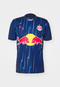 Maglia Puma Red Bull Salzburg a maniche corte, blu navy con motivo a lampi, logo circolare giallo e grafiche Red Bull, tessuto in poliestere.