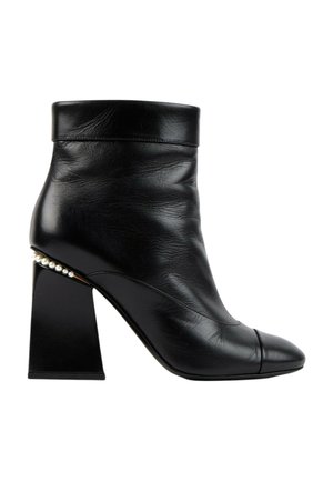 Bottine en cuir noir avec talon bloc et perles décoratives le long du bord du talon, avec un bout arrondi et un revers plié.