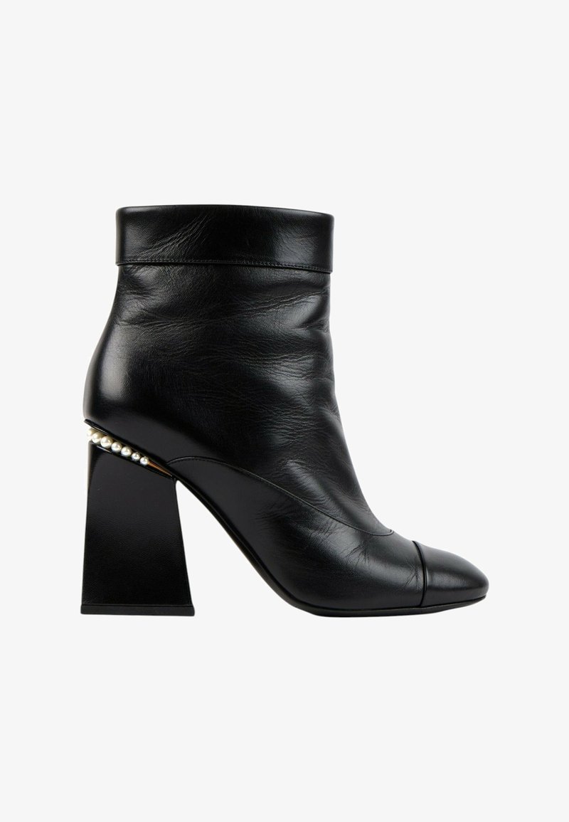 Bottine en cuir noir avec talon bloc et perles décoratives le long du bord du talon, avec un bout arrondi et un revers plié.