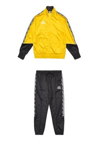 Geel jasje met zwarte mouwen, voorzien van een hoge kraag en een wit logo. Zwarte broek met een trekkoord, met patroonaccenten aan de zijkanten. Gemaakt van polyester.