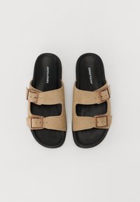 Beige semskede sandaler med to justerbare stropper og bronsefæs, med såle i kontrastfarge svart og minimalistisk design.