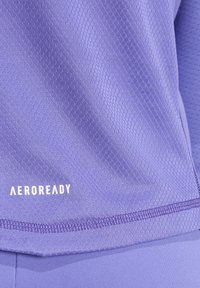 Paarse, vocht afvoerende sportshirt met een gestructureerd mesh-design. Voorzien van het "AEROREADY"-logo in het wit dicht bij de zoom. Zacht, flexibel stof.