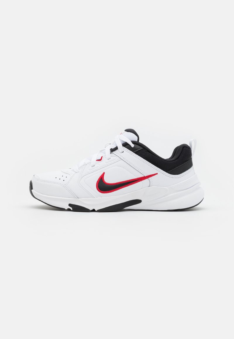 White athletic shoe with black accents, featuring a red Nike swoosh, lace-up front, cushioned sole, and mesh details for breathability.